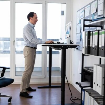 Mężczyzna pracuje przy biurku regulowanym stojącym w jasnym biurze.