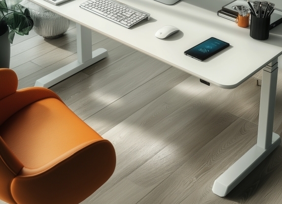 Biurko regulowane elektrycznie z pomarańczowym fotelem i akcesoriami na blacie.