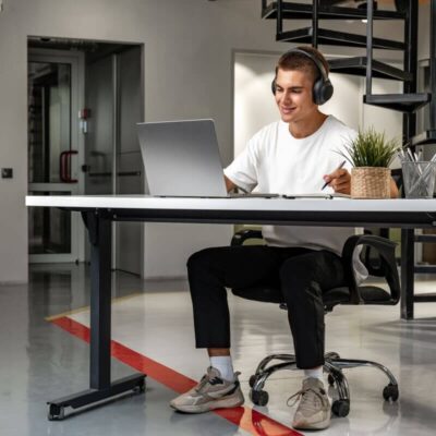 Mężczyzna pracuje przy laptopie na biurku elektrycznym w nowoczesnym biurze.